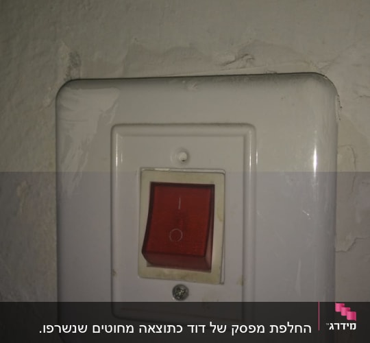 מתג חשמלי עם כפתור אדום על קיר